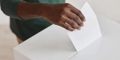 Closeup of a hand dropping a paper into a box
