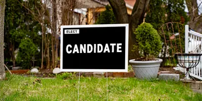 Black generic election sign on a lawn with a house behind